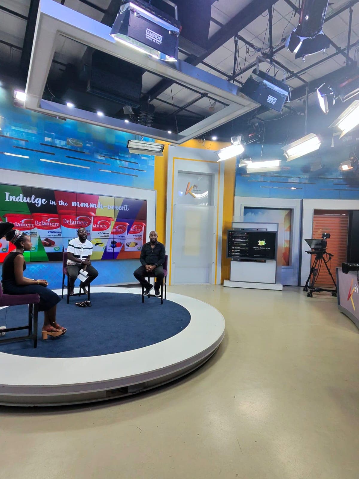 Keith Muoki seated with a presenter and another guest on the circular K24 Television studio set, under studio lighting rigs